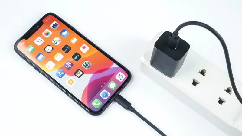 IPhone được sạc từ bộ sạc USB-C trên ổ cắm điện, kèm tai nghe